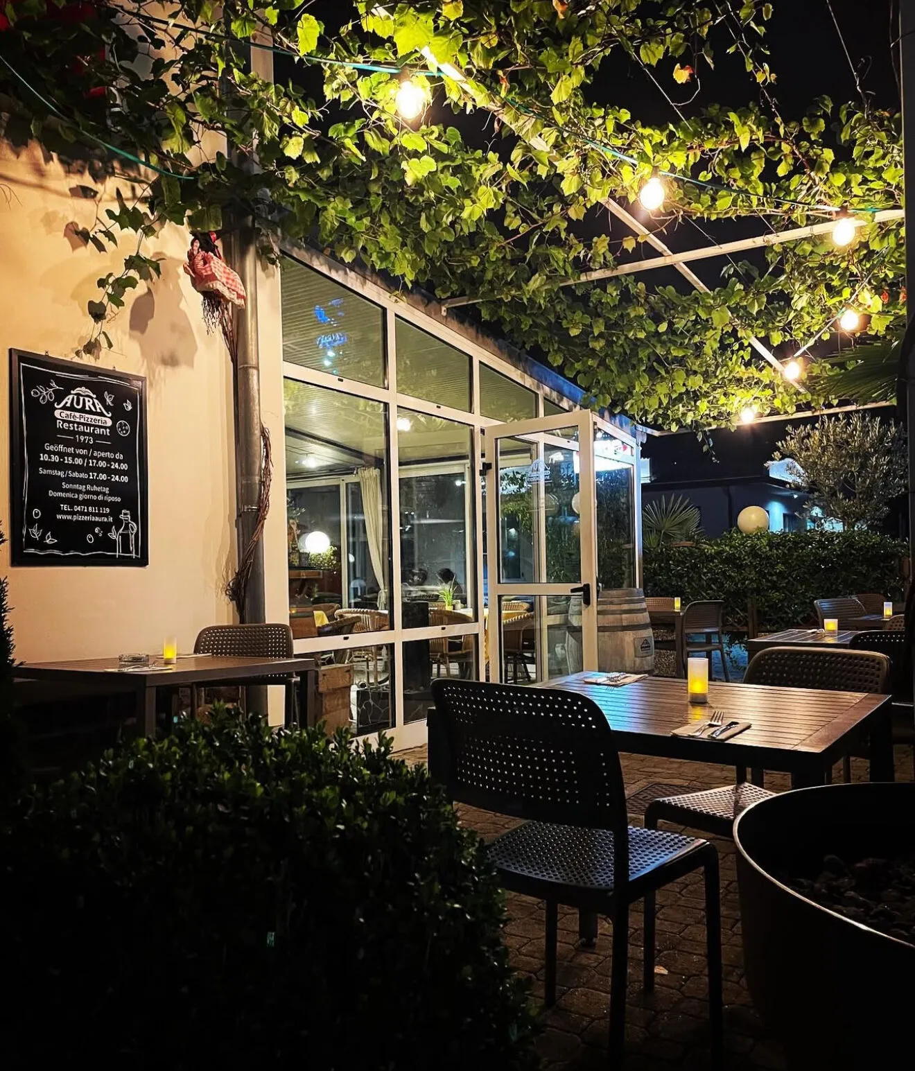 Begrünte Pergola mit Lichterketten am Abend
